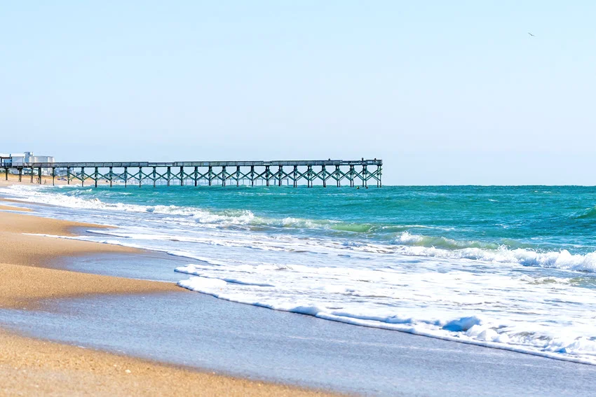 Clean beach view with a long pier stretching into the Gulf, a natural coastal visual for regional fishing sections and destination coverage in a US fishing guide.