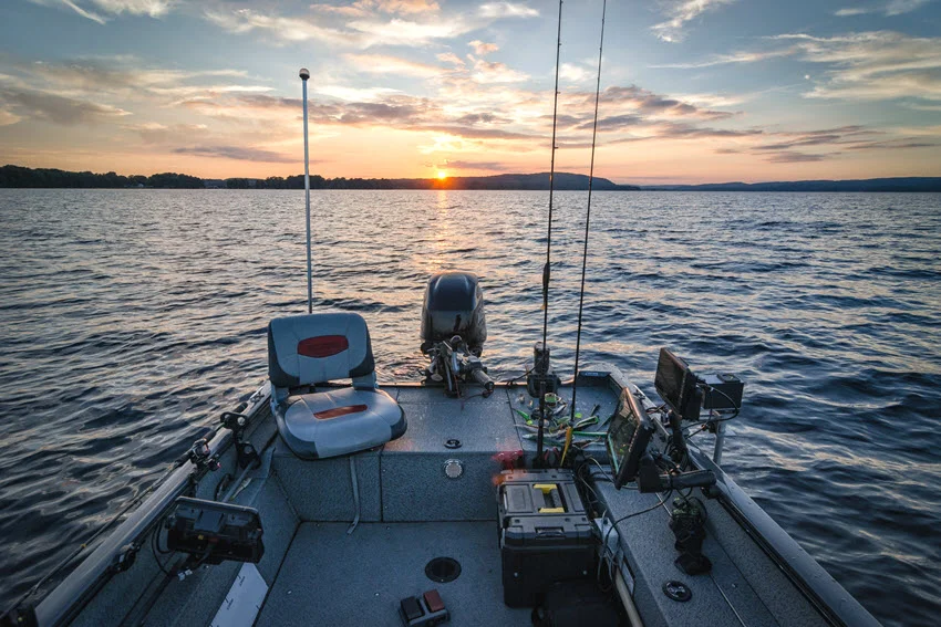 Stern view from a fishing boat at sunrise over calm water, a strong lifestyle shot for trip preparation, early departures, and offshore fishing adventure content.