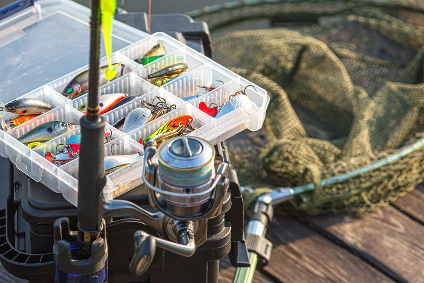 Bass fishing lures, spinning reel, rod, and landing net set up for a Florida freshwater trip targeting Largemouth Bass in lakes, canals, and rivers.