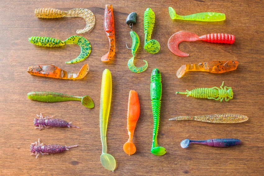 Group of colourful silicone lures on a wooden background, ideal for spinning fishing.