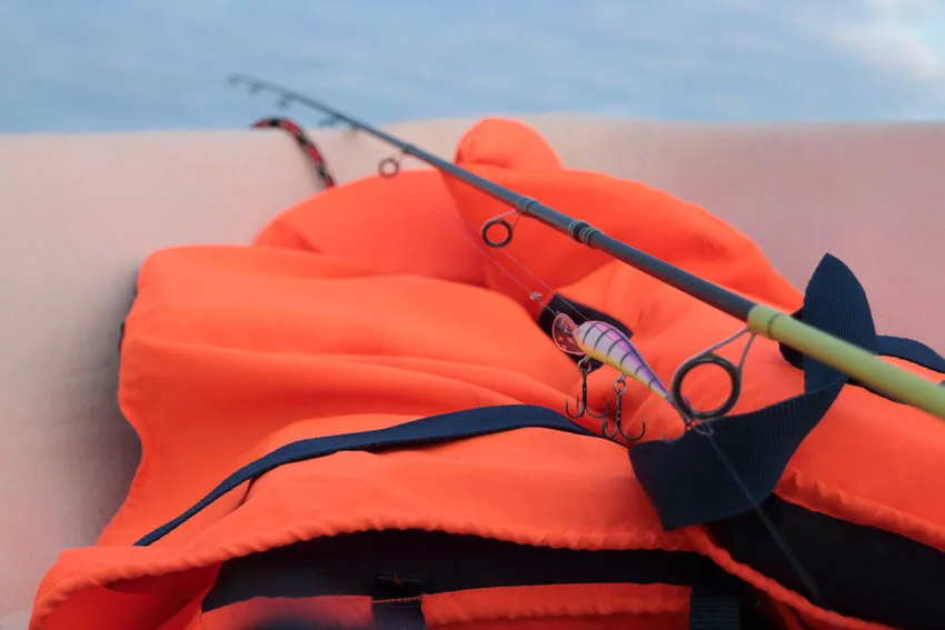 Fishing rod and life jacket on a boat, highlighting the importance of safety gear while fishing for predatory fish at sea.