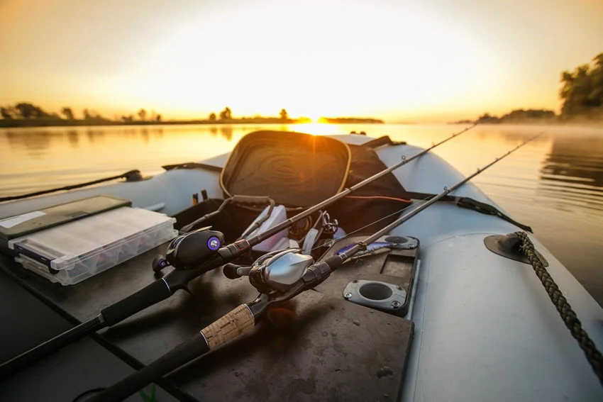 Close-up of a fishing reels positioned on a boat, with sunlight reflecting off its surface during sunset, highlighting the gear’s quality and creating a warm, glowing atmosphere.