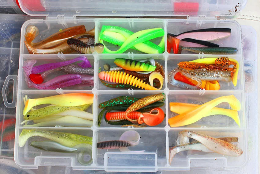 Top-down view of assorted soft plastic lures organized in a tackle box for targeting Flounder.