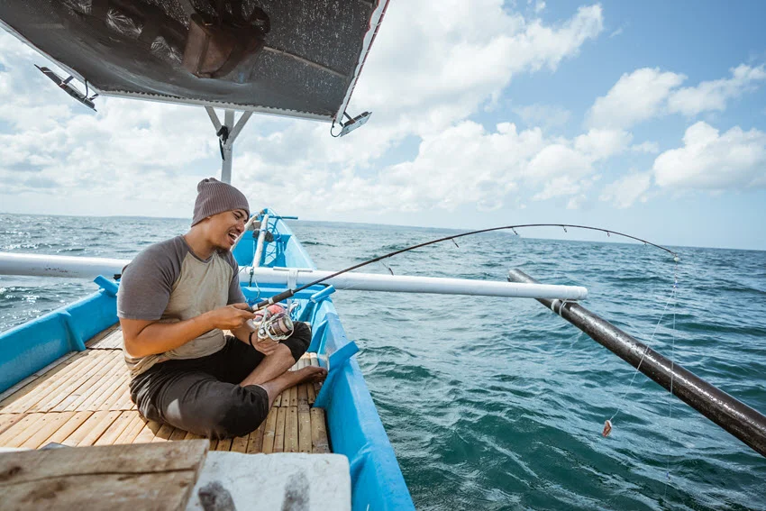 Happy angler jigging from a small boat with gear ready for a Flounder hookup.