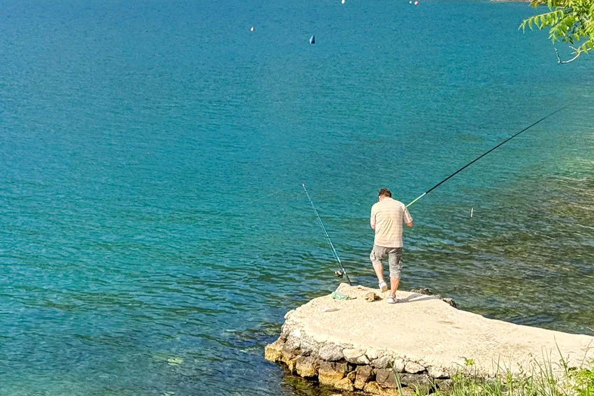 View of an angler casting from a concrete bank, illustrating lure fishing for Jack Crevalle in tidal rivers, canals, or estuaries.