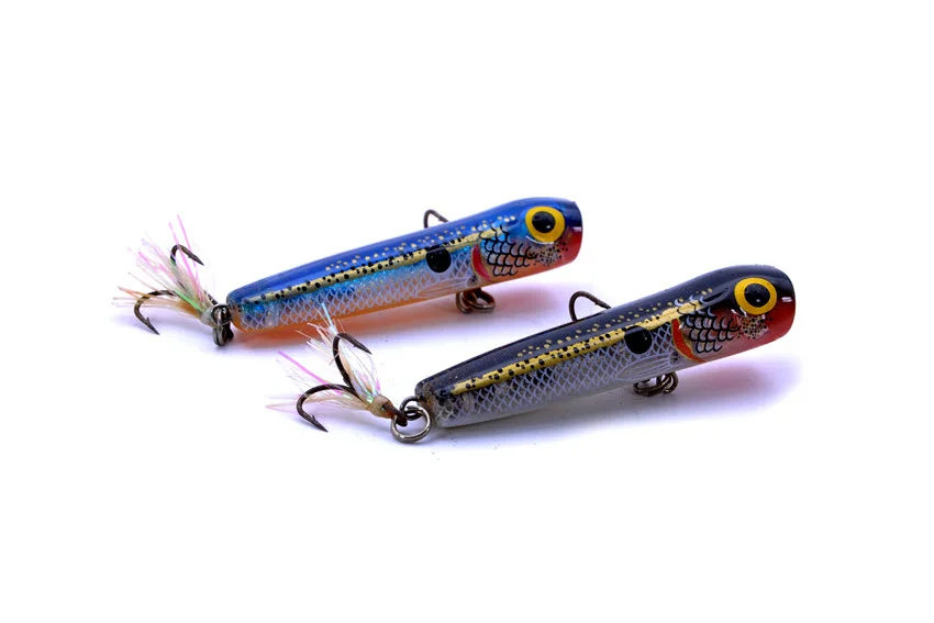 Close view of two colorful surface popper lures with treble hooks, designed to trigger explosive Jack Crevalle strikes on top.