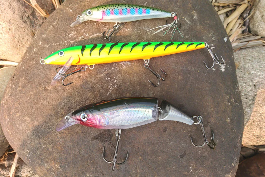 Close view of three colorful hard baits with diving lips and treble hooks, illustrating lure options for targeting King Mackerel.