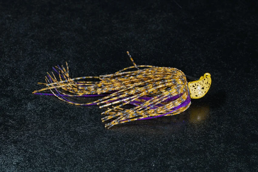 Close-up of a yellow spotted chatterbait fishing lure set against a dark background, highlighting its texture and design details.