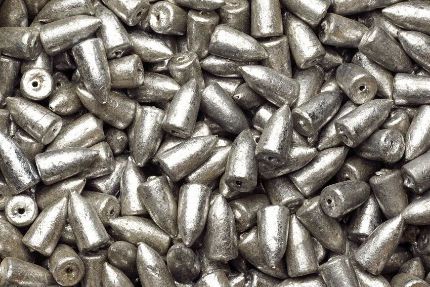 Close-up of a fishing bullet weight sinker, a small metallic accessory used to help lures sink efficiently during fishing, placed on a clean surface for detail view.