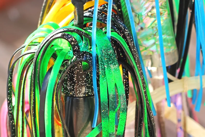 Close-up view of colorful trolling lures for catching Marlin, showcasing vibrant patterns, reflective skirts, and sturdy hooks, ready for offshore fishing.