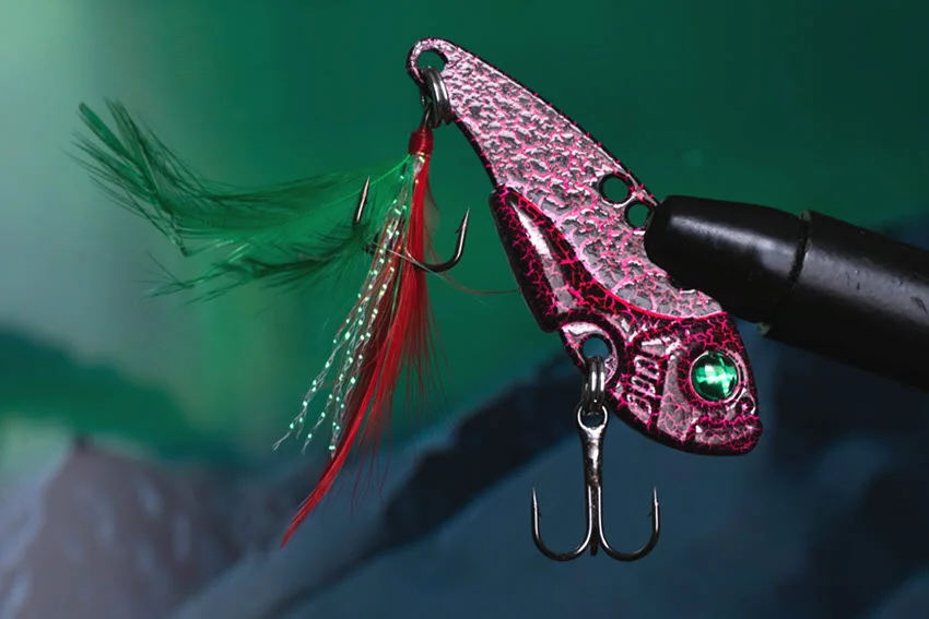 Close-up of a crankbait fishing lure with treble hooks and feather dressing, showing a flashy hard bait option for targeting Peacock Bass.