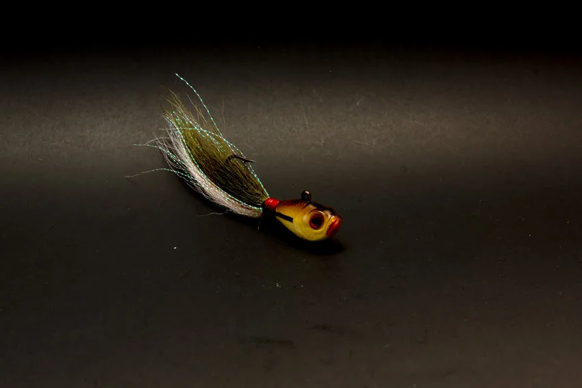 Bucktail jig head lure with hand-tied deer hair and fishing jig hooks isolated on black background.