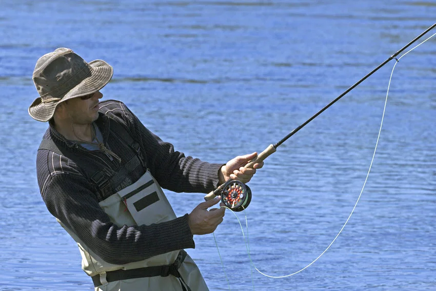 Fly fishing rod, reel, and Salmon flies beside the water, showing common lure-style gear used for targeting Salmon in rivers and clear freshwater areas.