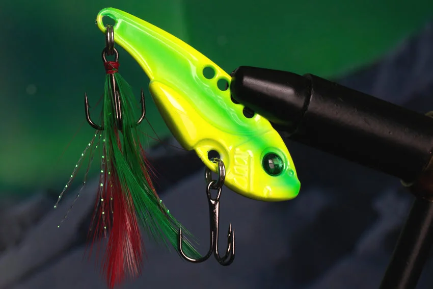 Focused shot of a bright chartreuse blade bait fitted with treble hooks and flash accents for fishing around Sheepshead structure.