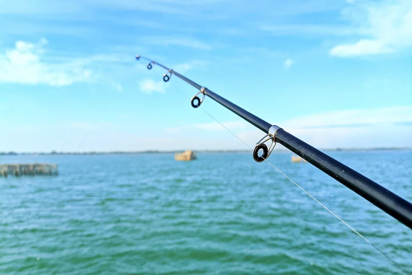 Close view along a fishing rod positioned over coastal water while targeting Sheepshead around submerged structure and productive bottom habitat.