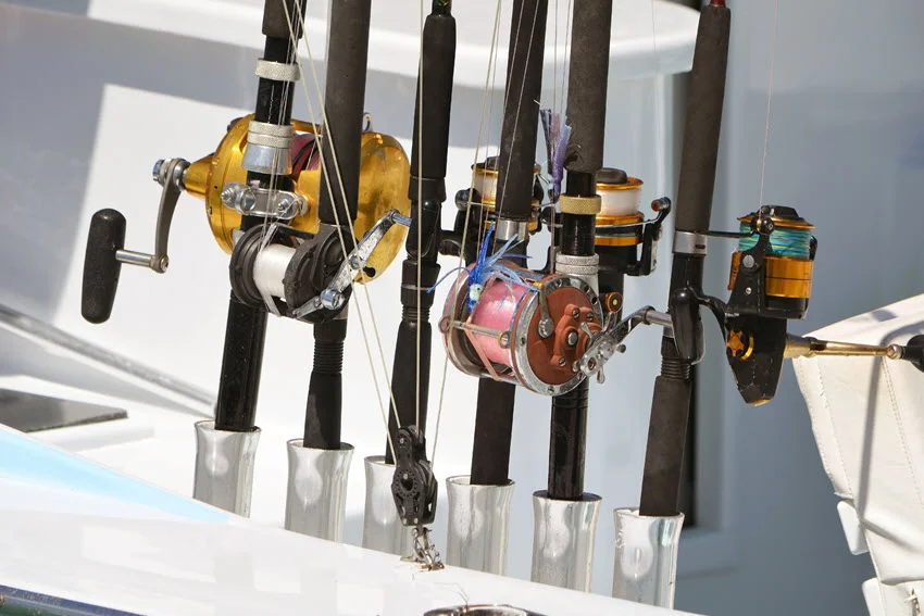 Close-up view of deep-sea fishing rods and reels securely mounted on the deck of a fishing boat.