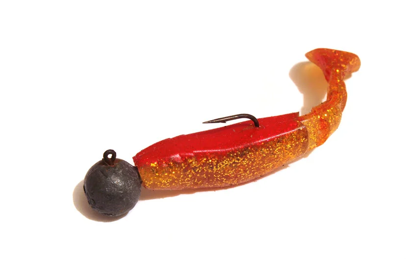 Orange jig bait with the hook placed on a white background.