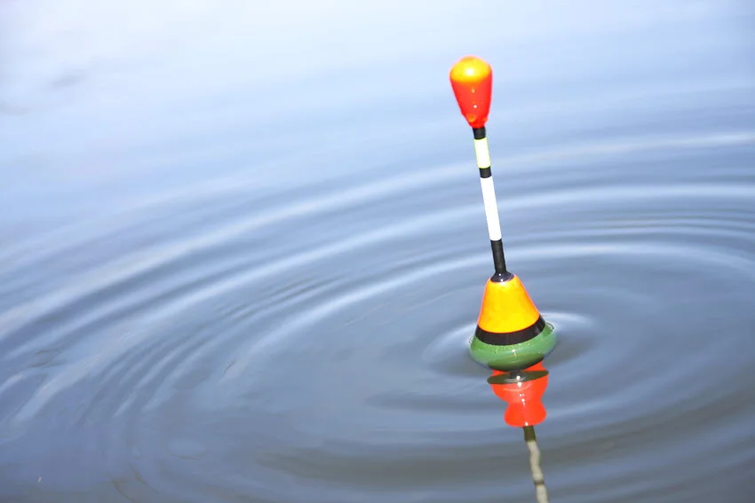 An orange-black-white topwater lure floating on the ocean surface.