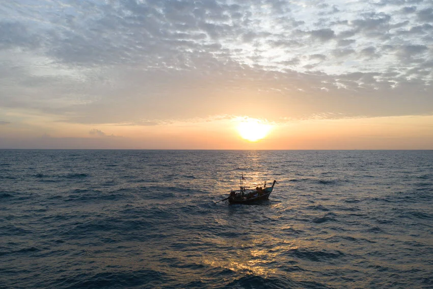 Small fishing boat drifting across open saltwater at sunrise, setting the scene for an early inshore trip when Snook can feed around moving water and low light.