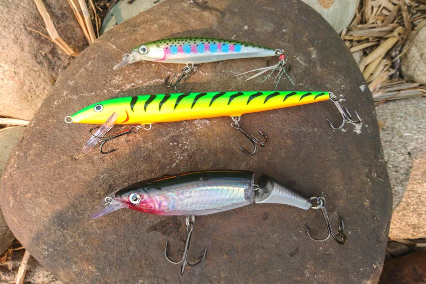 Set of bright hard lures arranged on a wooden surface ready for inshore and nearshore fishing.