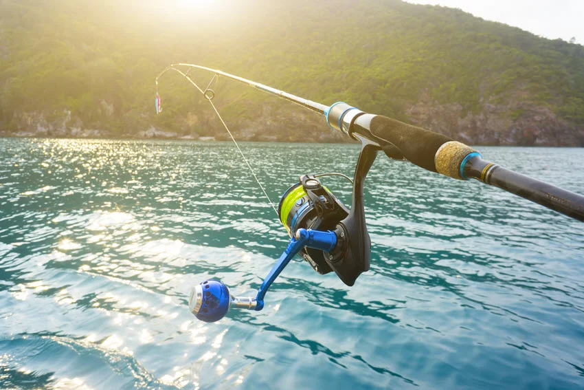 Fishing reel with a beautiful sunrise over an island in the background.
