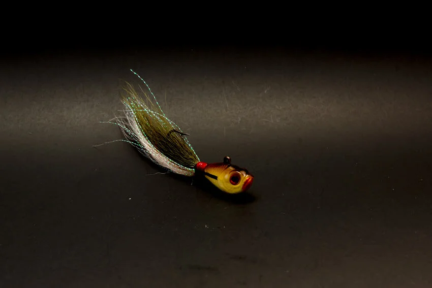 Close-up view of a bucktail Jig made with deer hair resting on an angler's hand under soft light.
