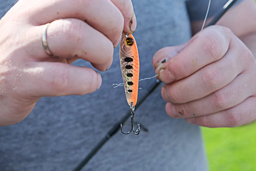 Male hands holding fishing line and hook, placing a crankbait.