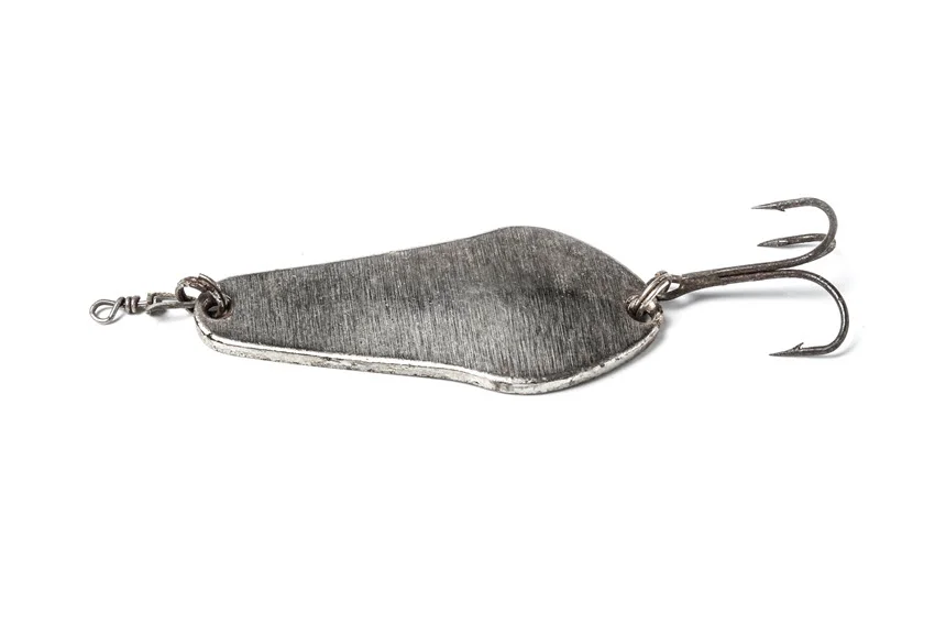 An old metal fishing spoon lure isolated on a white background, showcasing its worn texture and classic design used for attracting fish.
