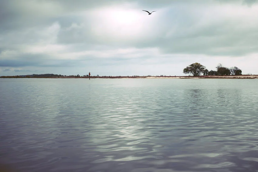 Panoramic view of Deer Island taken from a distance, with stormy clouds looming above and the island's outline visible against the moody sky.