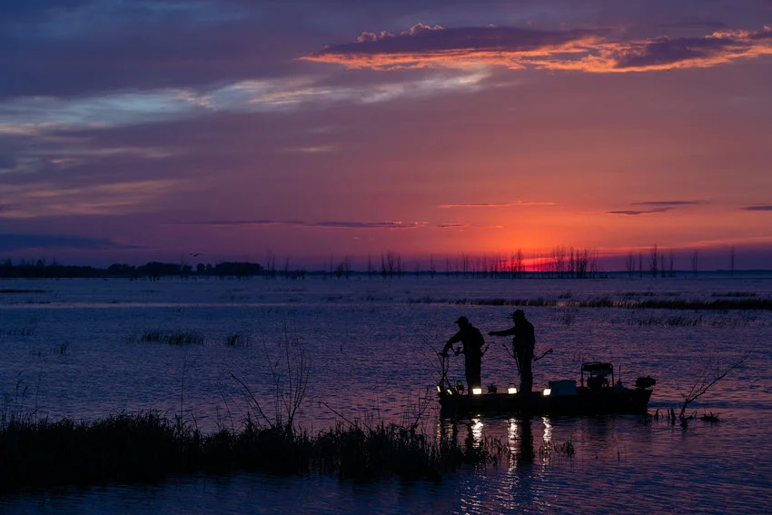 Distant shoot of two angler perfroming night bowfishing.
