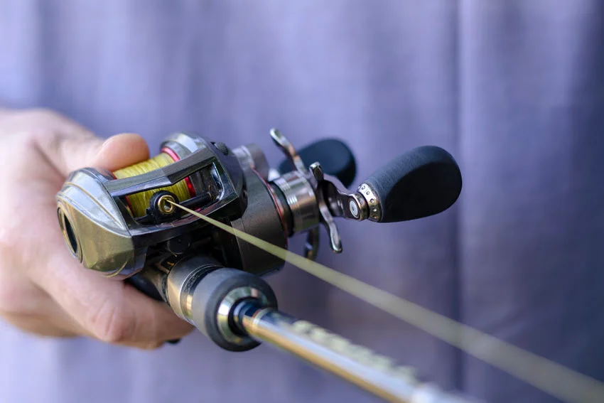 Close-up shot of hand-winding fishing reels held by a man.