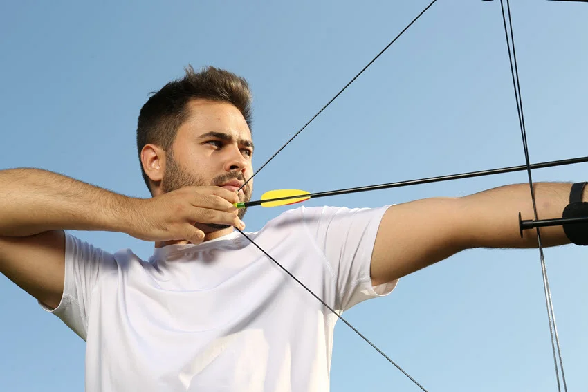 Close-up shot of a young angler practicing archery with a recurve bow, focusing on his stance and concentration.