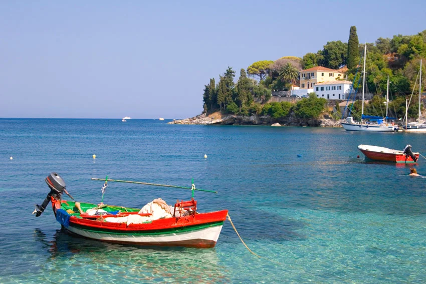 A colorful small fishing boat drifts gently while tied near the shore, floating on calm coastal water.