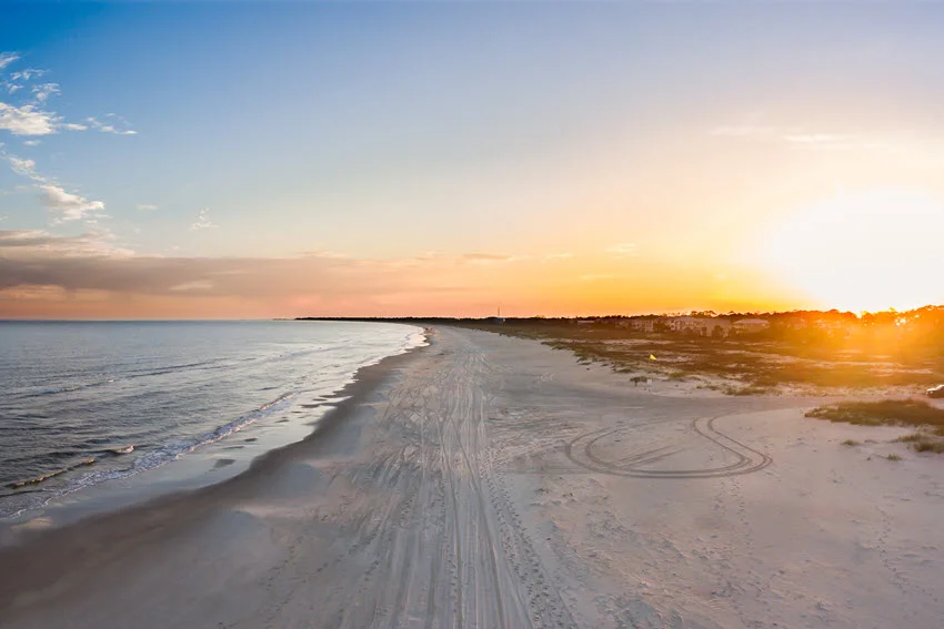 Panoramic view of the sandy Cape San Blas Beach, featuring a stunning sunset and a clear sky.
