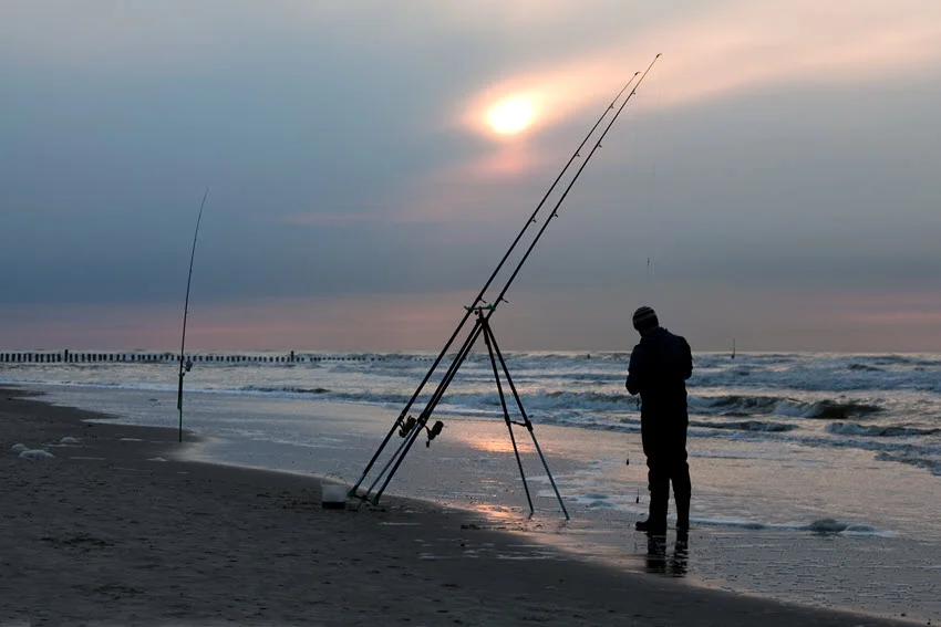 Cloudy sky above an angler setting up his fishing rods for shore fishing.