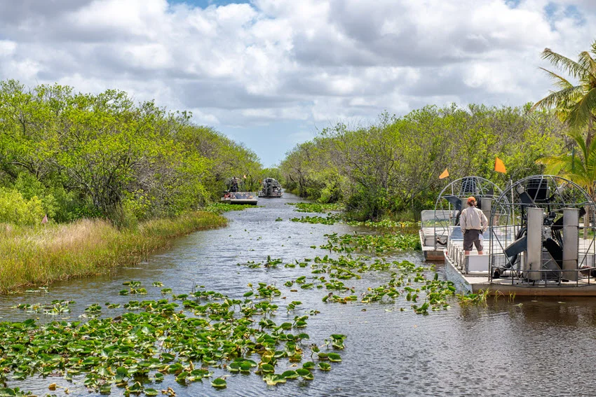 Wide shot of a fishing charter boat navigating the calm waters of a picturesque lake in Everglades National Park.