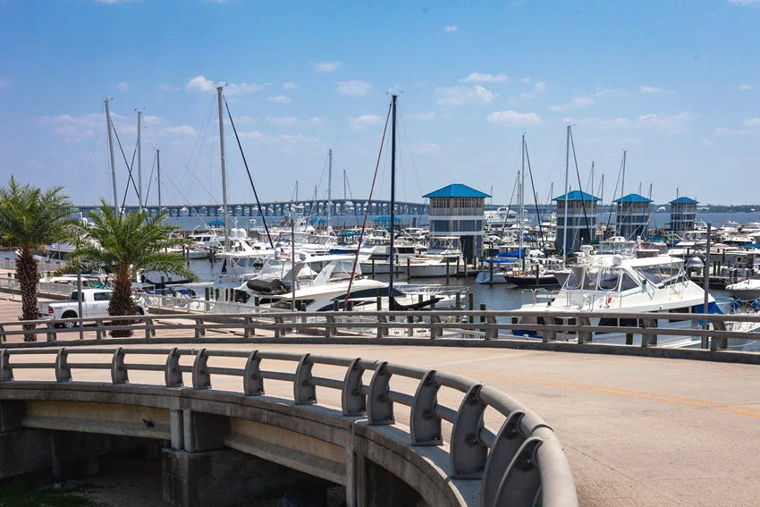 Bay St. Louis Small Craft Harbor, showcasing rows of boats docked along wooden piers with calm waters reflecting the clear sky.