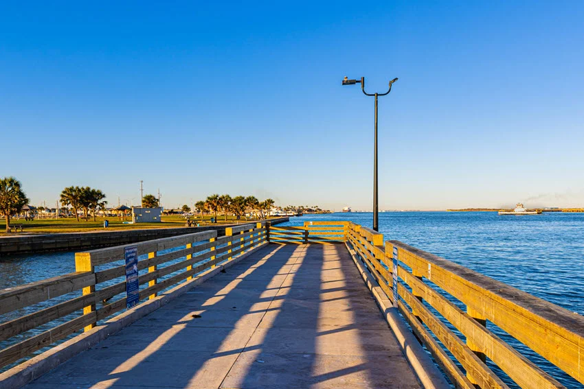 Fishing pier in Corpus Christi, Texas, extending over the calm coastal waters. The wooden structure provides a scenic spot for anglers and visitors to enjoy fishing and ocean views against the backdrop of the Gulf of Mexico.
