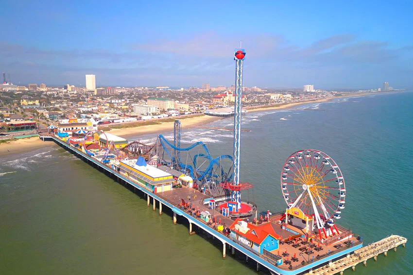 Aerial view of Galveston Island Historic Pleasure Pier in Texas, USA. The amusement pier extends over the Gulf of Mexico, featuring thrilling rides, colorful attractions, and stunning ocean views.