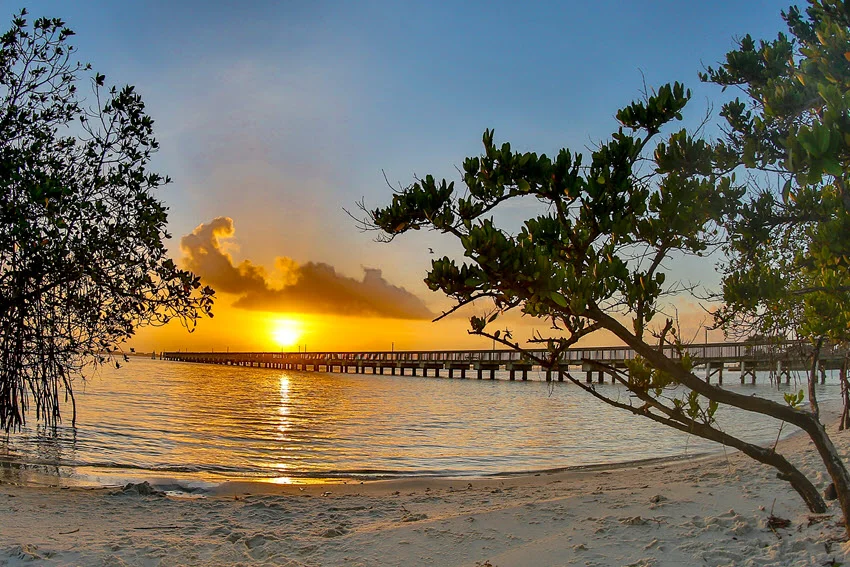Early morning sunrise at a fishing pier in Jensen Beach, Florida, with soft warm light reflecting off calm waters, creating a peaceful and picturesque start to the day.