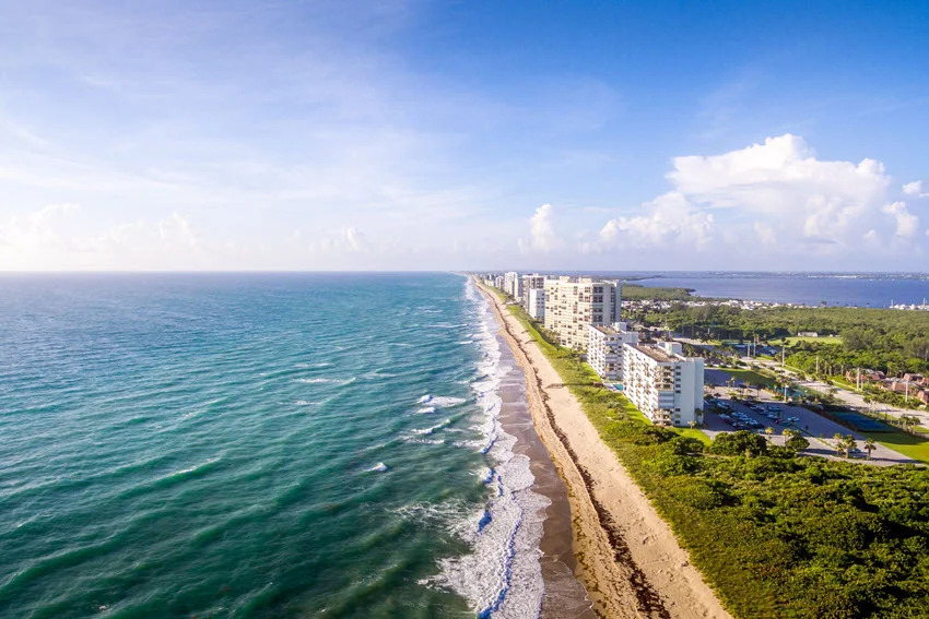 A scenic view of the beautiful Jensen Beach in Florida on a sunny summer day, with clear skies and gentle waves.