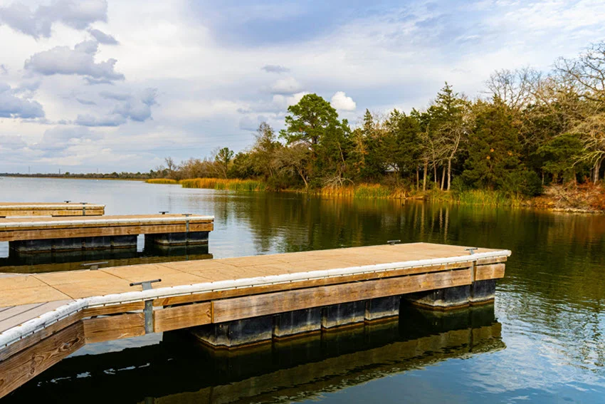 View of Frank's Fishing Pier with wooden docks extending over calm water surrounded by trees.