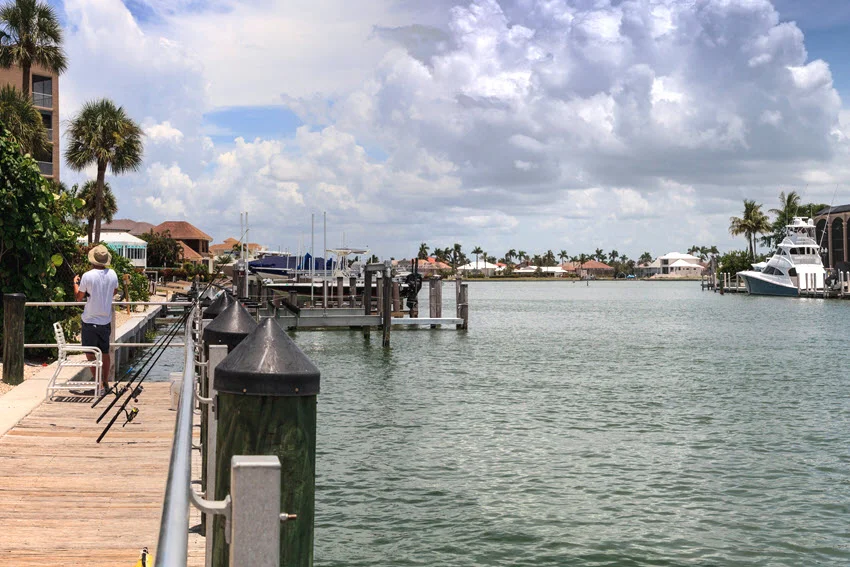 Scenic view of the fishing pier off Caxambas Park on Caxambas Island, near Caxambas Pass, on a sunny day in Marco Island, Florida. The pier extends into the clear blue waters, surrounded by lush greenery and providing a tranquil spot for fishing and enjoying the natural beauty of the area.