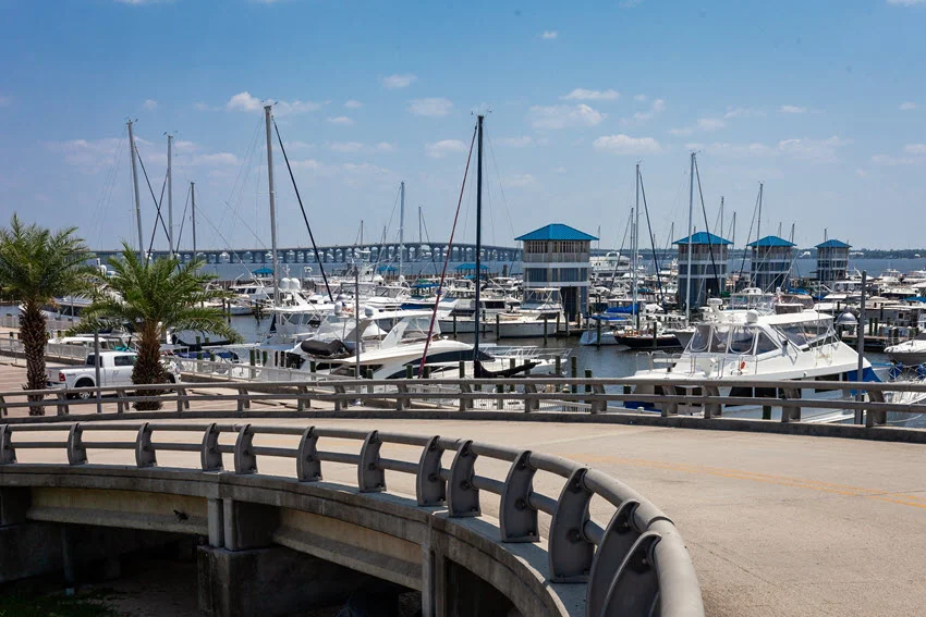 A beautiful fishing pier extending into the tranquil waters of Bay St. Louis, Mississippi. The wooden pier offers a scenic coastal view, with calm waves gently lapping against its supports under a clear blue sky.