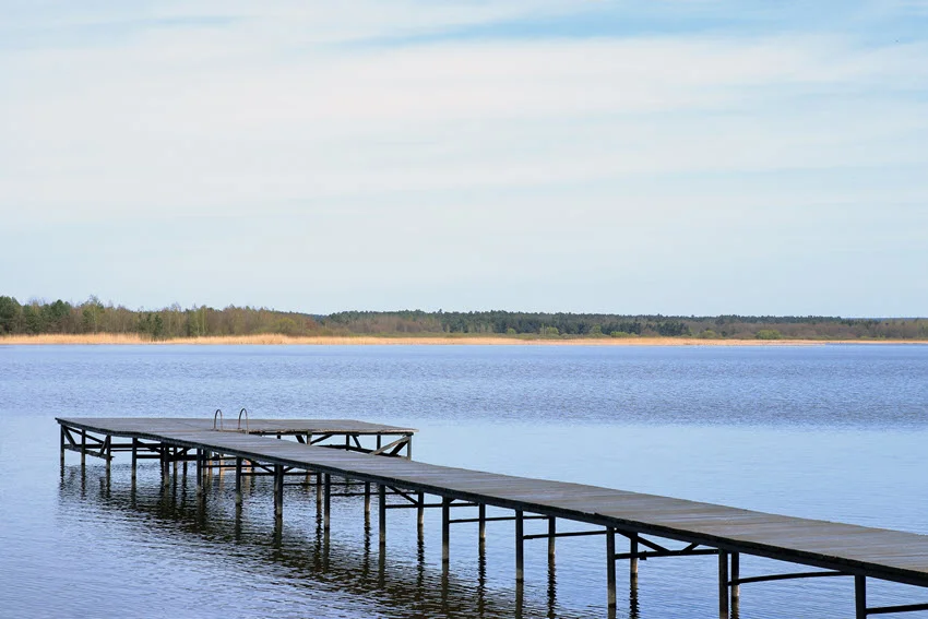 A peaceful lakeside pier surrounded by calm water and trees near Ocean Springs, Mississippi.