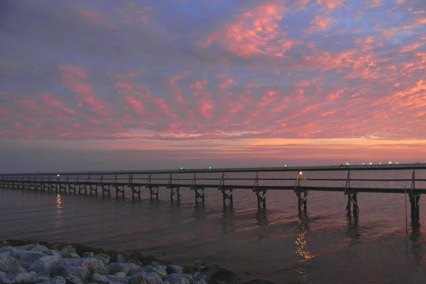 A fishing pier along the shoreline in Rockport, TX, with calm coastal waters and a scenic horizon.