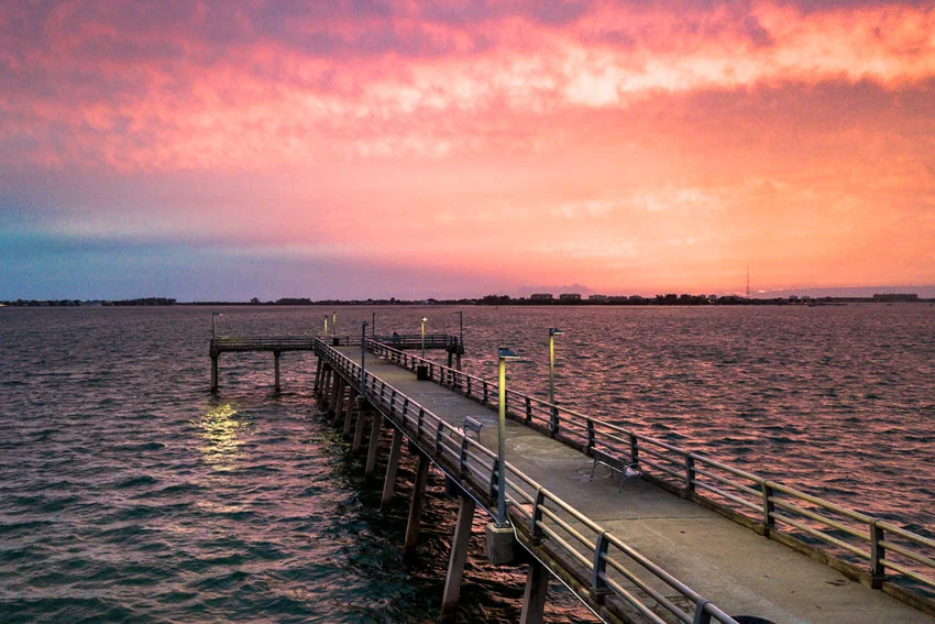 Pier view in Sarasota, Florida, with sunset colors glowing in the background and a peaceful shoreline setting.
