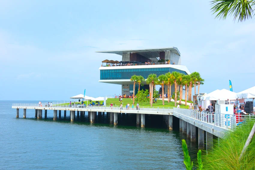 Close-up view of the modern St. Pete Pier in Saint Petersburg, Florida, featuring sleek architecture and waterfront restaurants with outdoor seating overlooking the bay.