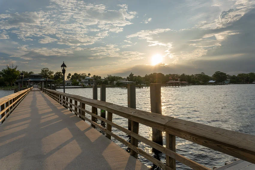 View of a public pier in Florida at sunset, with a covered pavilion and boat slips along the water. The warm glow of the sunset adds to the peaceful atmosphere, making it an ideal spot for relaxation and recreation.