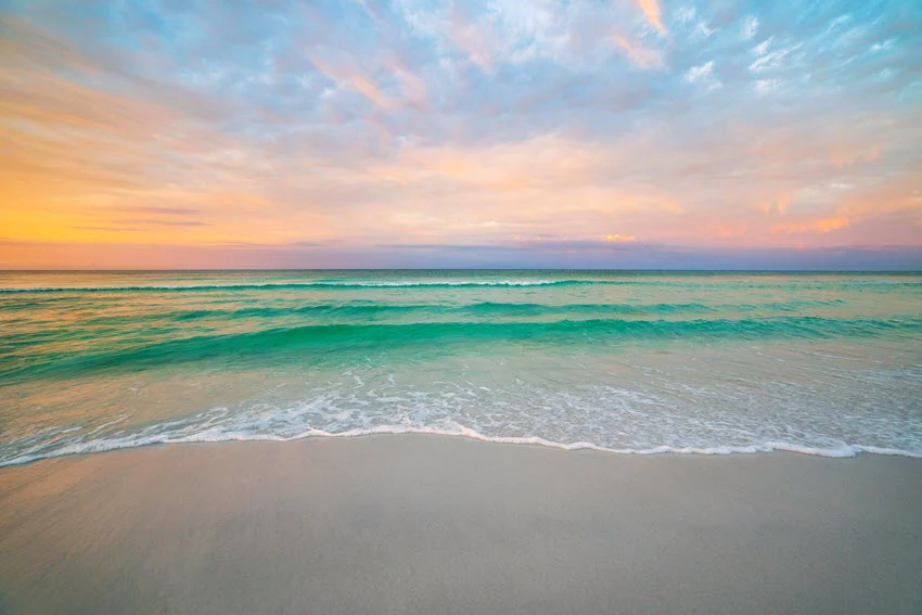 Sunrise shot of Destin's sandy beach, with mild waves gently splashing the shore.